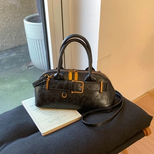 Detail of vintage black bowling handbag featuring cracked leather texture and golden buckles