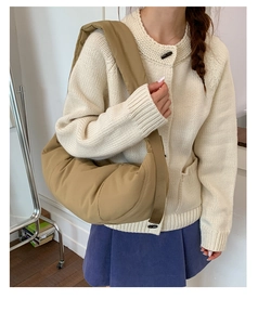 Detail of quilted khaki nylon crescent bag with a wide shoulder strap worn by a model