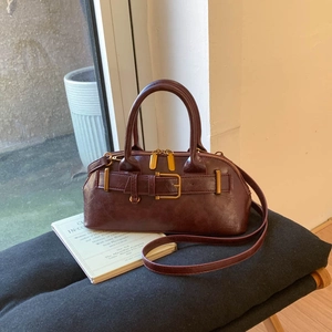 Macro shot of dark burgundy Boston bag with retro textured leather and metallic zipper details
