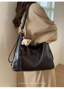 Detail of vintage brown leather hobo bag with gold logo and cute puppy pendant