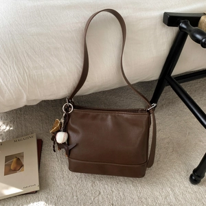 Detailansicht der dunkelbraunen Leder-Beuteltasche mit Baseball-Anhänger und feinen Nähten