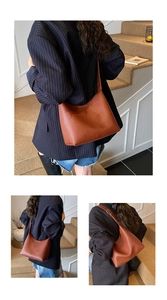 Detail of a brown lychee pattern leather Hobo bag with adjustable strap and metal buckle