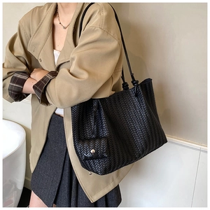 Detail of black woven tote bag with V-shaped texture and a matching mini pouch