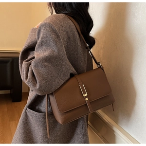 Close-up of brown litchi pattern leather square bag with gold vertical metal buckle