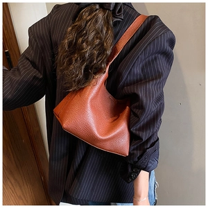 Close-up of brown lychee grain leather bucket bag with minimalist wide shoulder strap