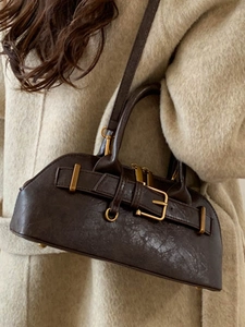Retro dark brown leather handbag with metallic buckle shown on a stylish beige coat