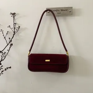 Detailansicht einer burgunderroten Wildledertasche mit einer goldenen Metallschnalle