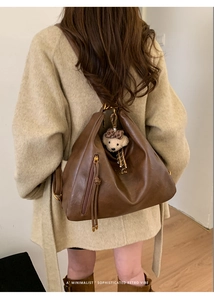 Brown leather tote bag featuring a decorative fringe zipper and cute bear charm pendant