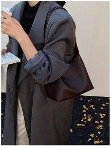 Detail of dark brown lychee texture leather bucket bag worn with autumn coat
