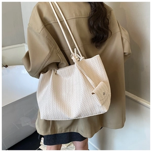 Detail of cream woven tote bag showing V-pattern texture and detachable mini pouch