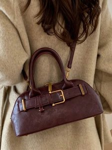 Elegant burgundy Boston style handbag with vintage gold buckle on beige wool coat