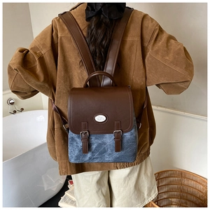 Detaillierte Rückansicht eines Retro-Rucksacks aus blauem Stoff und braunem Lederriemen