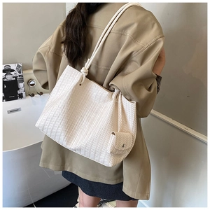 Detail of cream woven tote bag featuring a matching mini pouch and knotted handle design