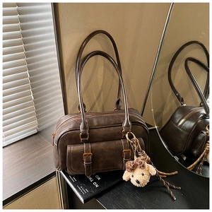 Detailed macro of vintage dark brown faux leather bag with double buckles and plush charm