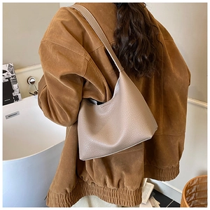 Close-up of taupe litchi grain leather texture on a minimalist hobo shoulder bag