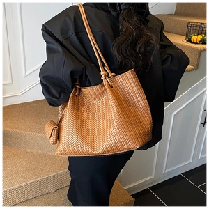 Close-up of caramel woven tote bag featuring chevron pattern and knot detail