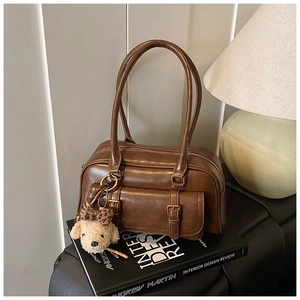 Close-up of a retro brown bowling bag with a cute plush charm on interior design books