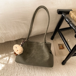 Detail der olivgrünen Wildleder-Tote-Bag mit Trageriemen und niedlichem Plüschtier-Anhänger
