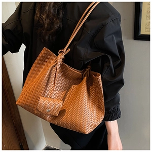 Close-up of brown woven tote bag featuring detailed herringbone texture and matching pouch