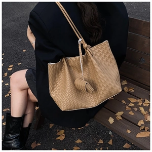 Detail of light brown woven tote bag with herringbone pattern on a wooden bench