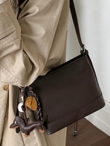 Dunkelbraune Eimer-Tasche für Damen mit Baseball- und Bärenanhänger zum beigen Mantel