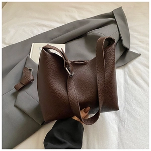 Detail view of deep brown lychee grain leather texture and silver metal buckle on a bag
