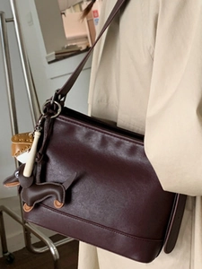 Retro-Eimerbeutel in tiefem Burgund mit Dackel-Anhänger am Modell im beigen Mantel