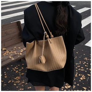 Detail of khaki woven tote bag showing tight chevron texture and leaf pendant