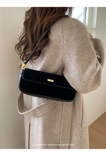 Sac baguette noir minimaliste porté avec un manteau en laine dans un style urbain chic