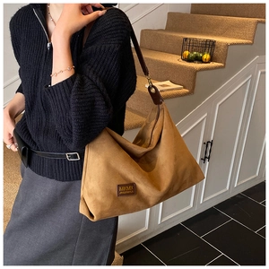 Gros plan sur un grand sac cabas en daim marron avec écusson MKMX et bandoulière vintage
