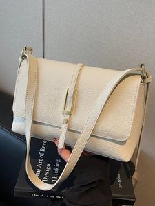 Minimalist beige pebble leather crossbody bag with a sleek gold buckle and slim strap