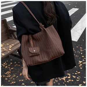 Detail of dark brown woven tote bag with matching mini pouch on casual street background