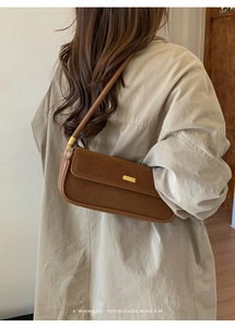 Détail d'un sac à bandoulière en daim marron montrant la texture et la boucle dorée