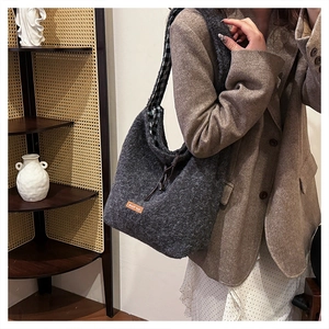 Detail of grey wool felt tote bag with orange label and black-white checkered lining