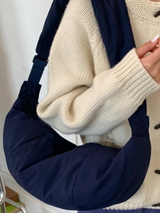 Navy blue nylon crescent crossbody bag with quilted puffer texture and wide shoulder strap