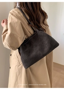 Detail der dunkelgrauen Wildledertasche mit weißen Ziernähten und beigem Trenchcoat-Look