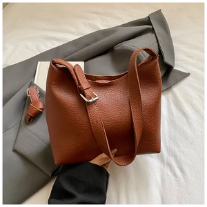 Detail view of brown lychee grain leather bucket bag with adjustable shoulder strap