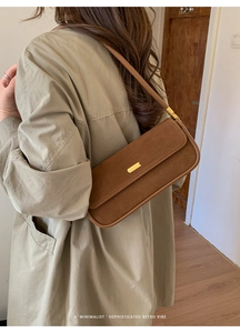 Détail du sac baguette en daim marron avec boucle magnétique dorée et bandoulière en cuir
