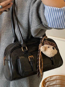 Chic black faux leather Boston bag with teddy bear charm and front pocket shown on model