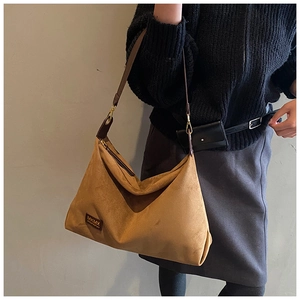 Détail d'un sac cabas vintage en daim marron avec étiquette de marque et boucle métal