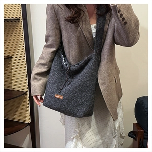 Detail showing plush dark grey wool texture and OUR LOVE leather patch on shoulder bag