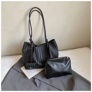 Detail of black woven tote bag featuring a matching leather inner pouch and knot strap