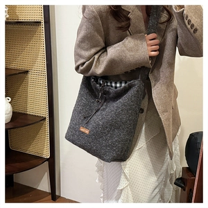 Detail view of dark grey fuzzy bucket bag with drawstring closure and interior check lining