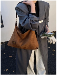 Détail du sac cabas en daim marron avec logo MKMX en cuir et bandoulière réglable