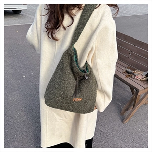 Detailed macro view of dark green plush bucket bag with fuzzy texture and brand tag detail