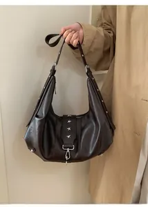 Detail view of dark brown leather tote bag with silver star hardware and metal rivets