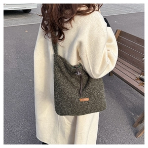 Detail of dark green fuzzy crossbody bag with drawstring and orange our fave label