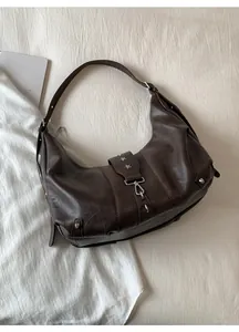 Detail of dark brown leather hobo bag featuring vintage texture and silver star rivets