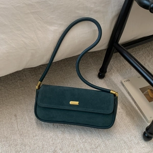 Minimalistische dunkelgrüne Wildleder-Achseltasche mit Gold-Schnalle auf Teppich