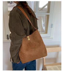 Detailed close-up of brown suede tote bag with golden metal swivel clasp and leather strap